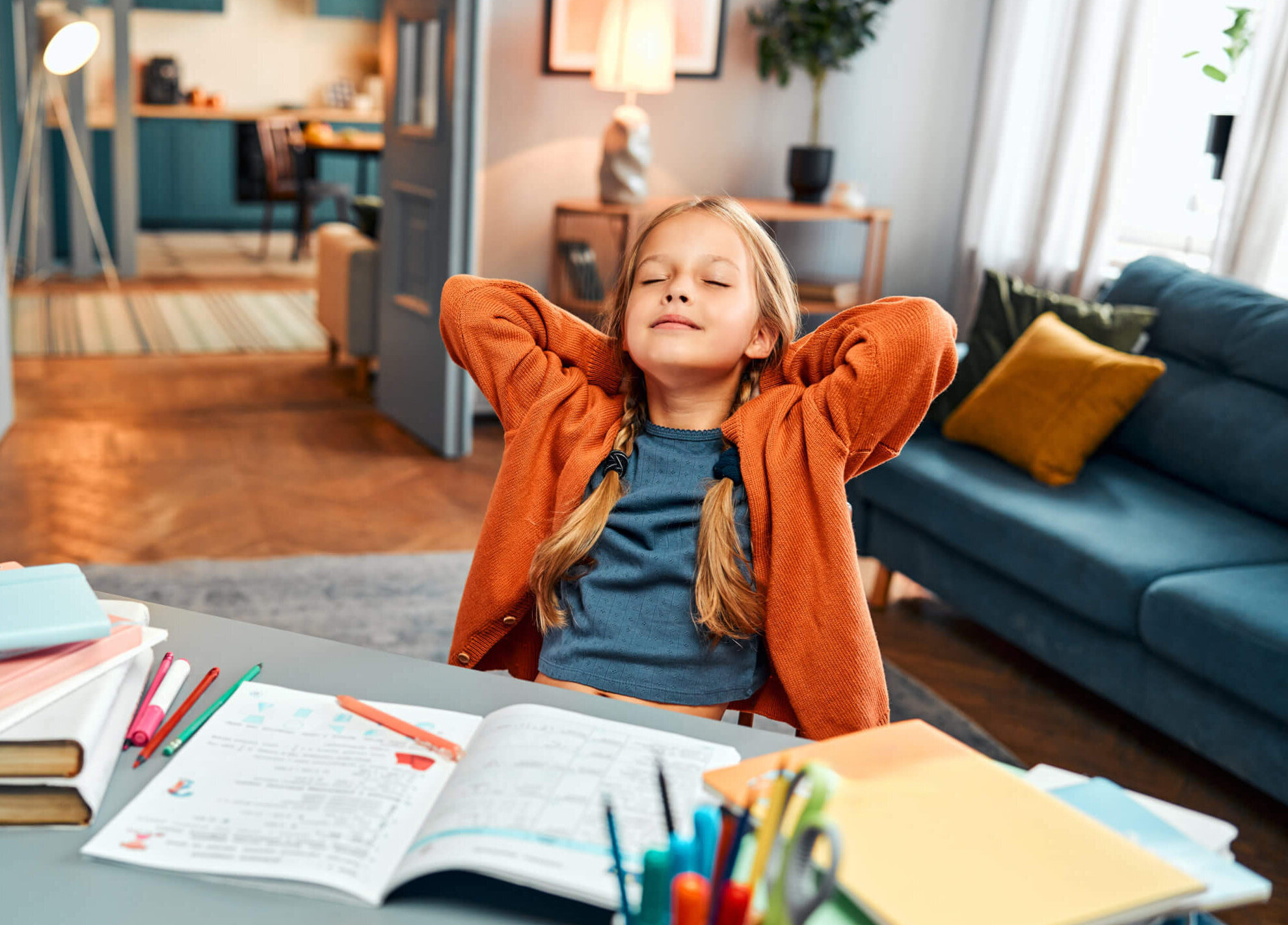 Completed homework. Relaxed little girl in home clothes leaning on back of chair by desk with closed eyes Completed homework. Relaxed little girl in home clothes leaning on back of chair with hands behind head and closed eyes. Calm kid finishing daily self studying by desk with coloured stationery.