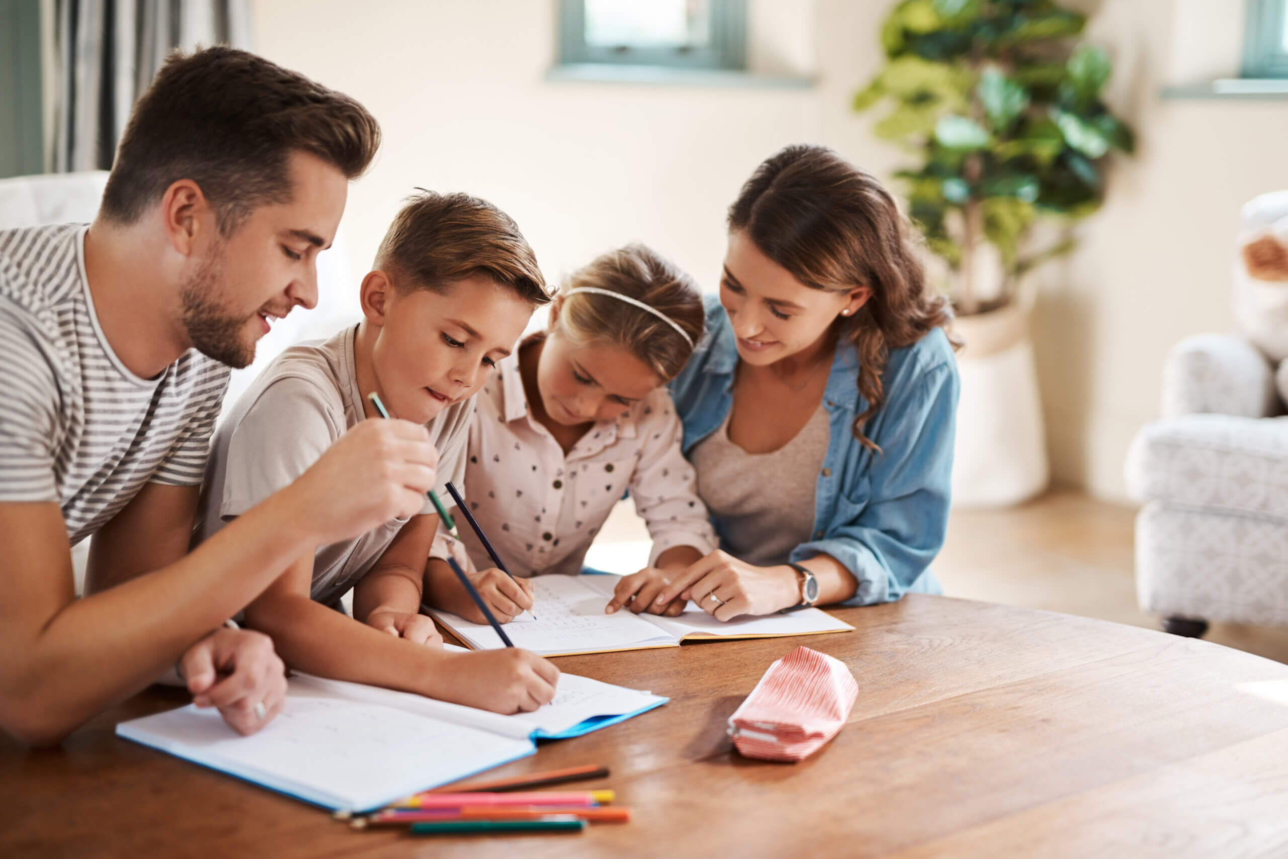 Shot of a happy young family of four doing homework together. Shot of a happy young family of four doing homework together.