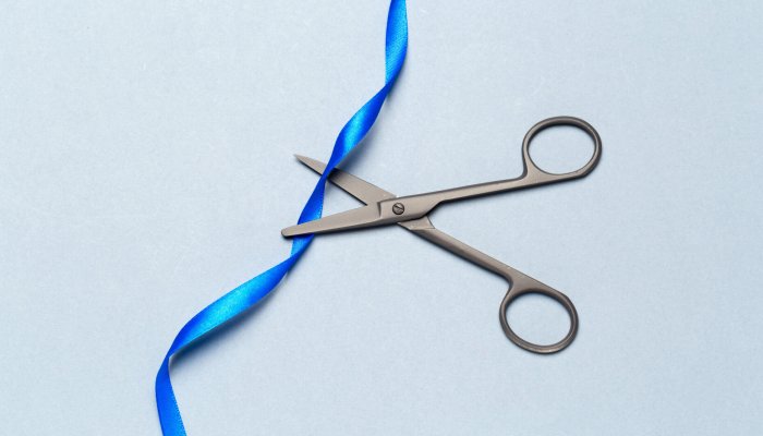 Grand Opening illustrated with scissors and a blue ribbon on a gray background Bändertrennung als Energiearbeit